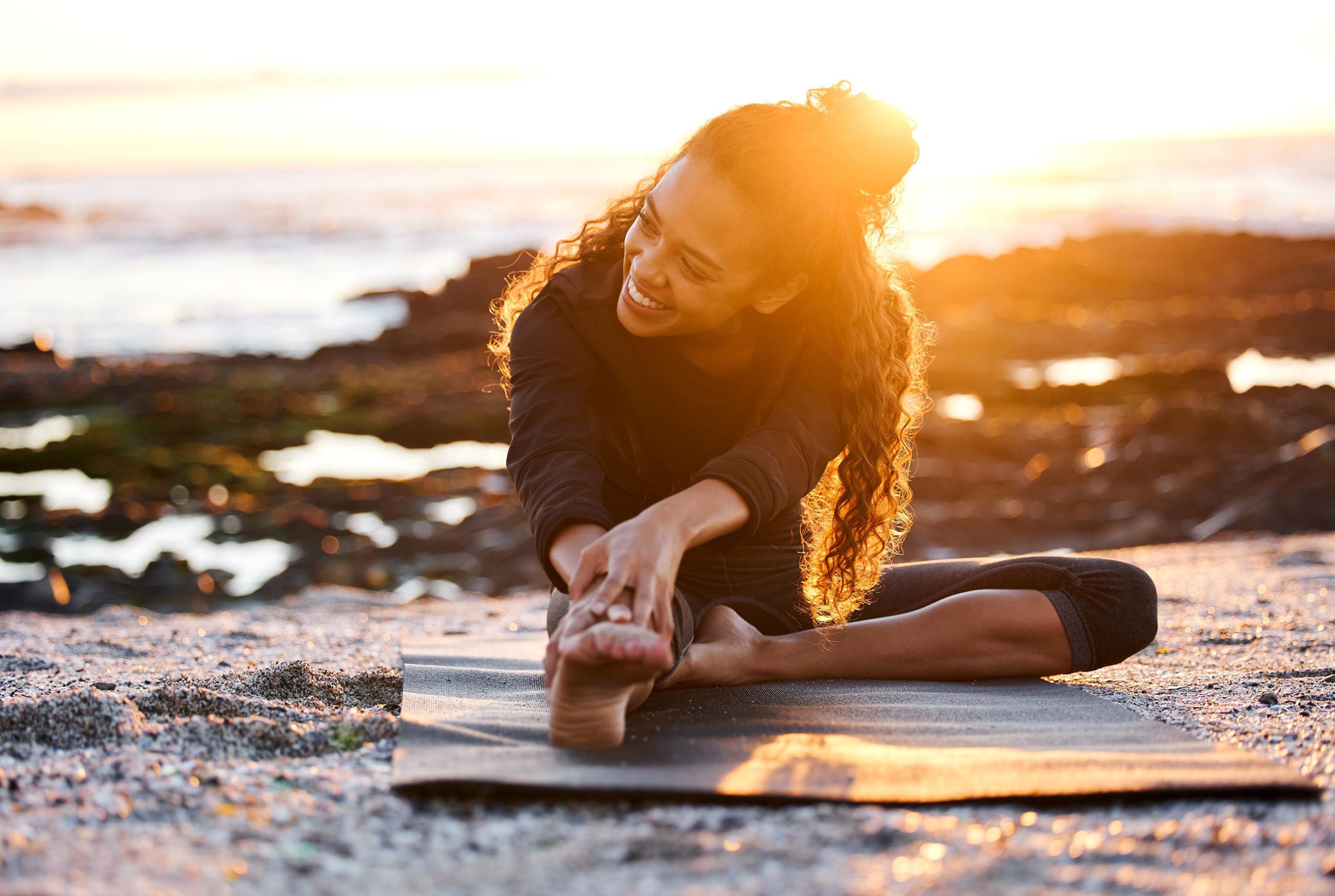Woman stretching on a yoga mat on the beach
